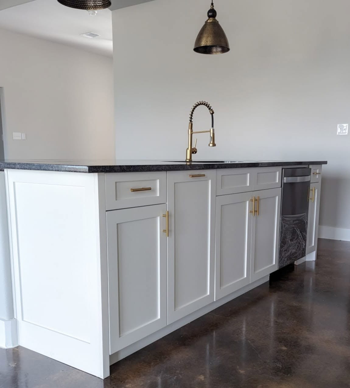 Brass bar pulls with a matching brass gooseneck faucet on a kitchen island