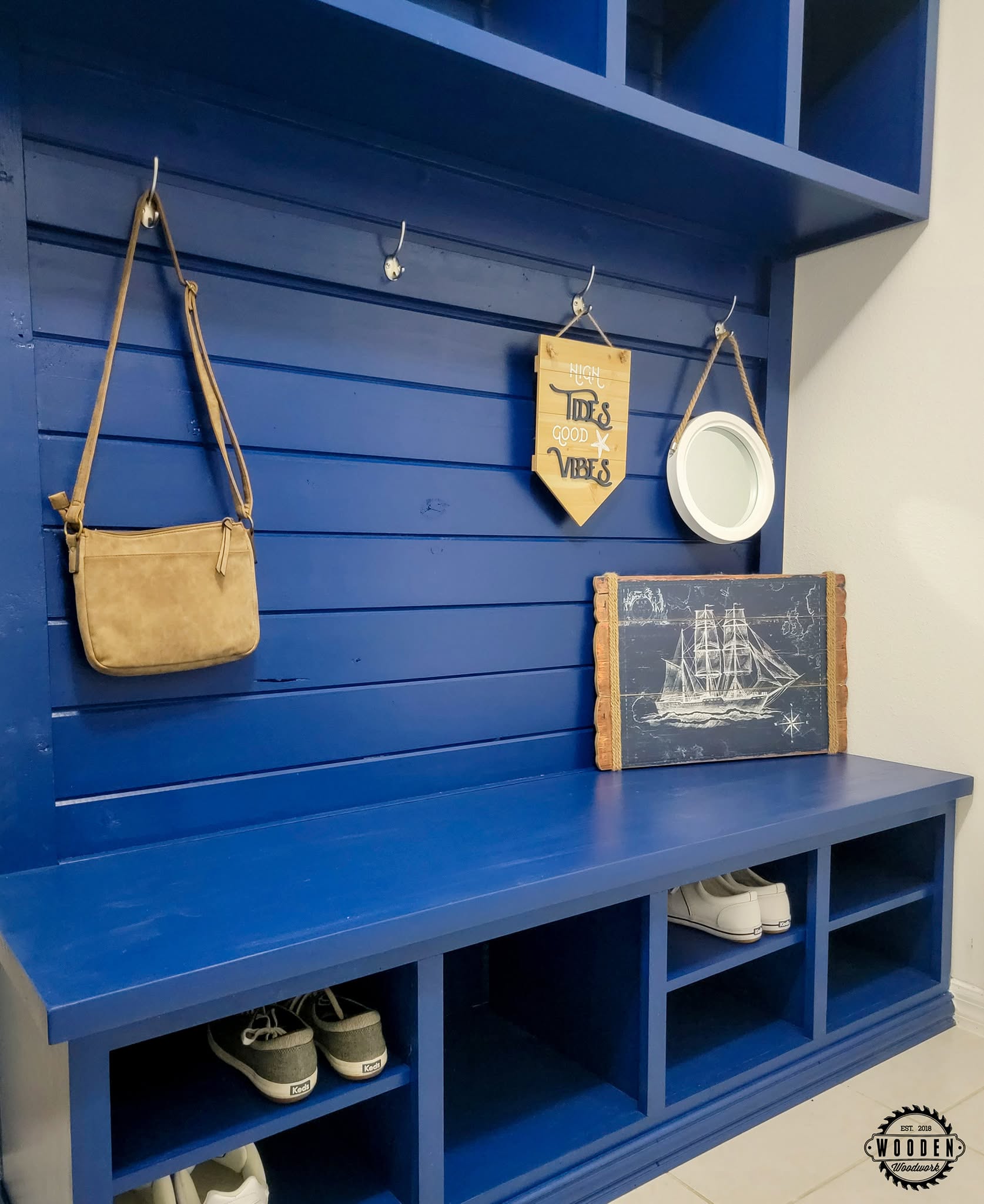 Silver-tone coat hooks on a blue shiplap hall tree