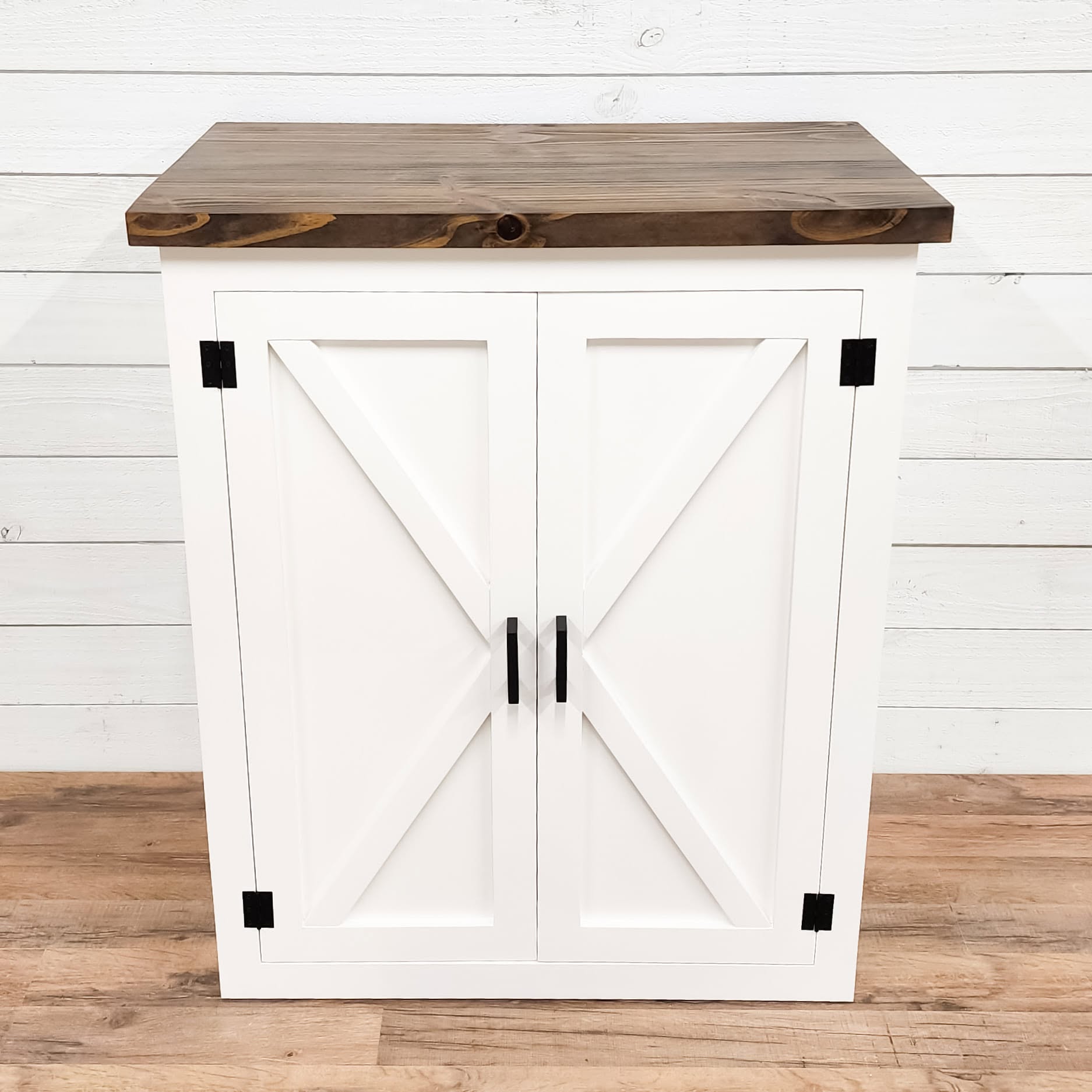 Black square corner brackets on a white barn-door style cabinet