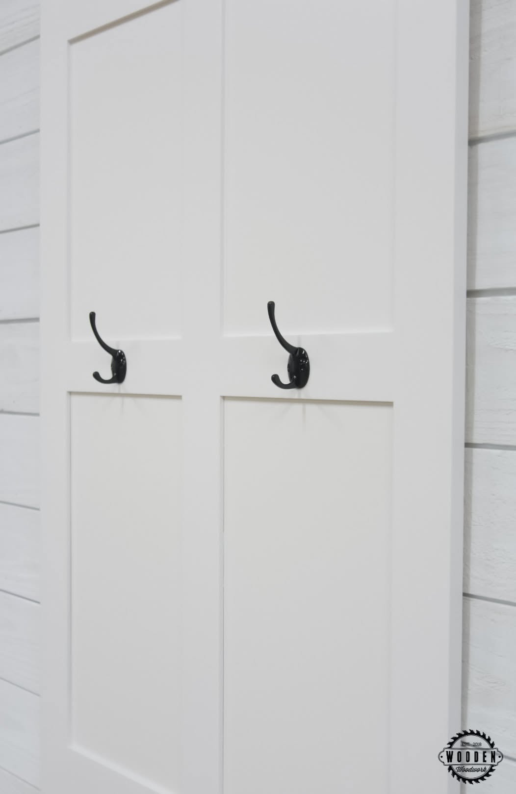 Black oval-back double coat hooks on a white paneled door