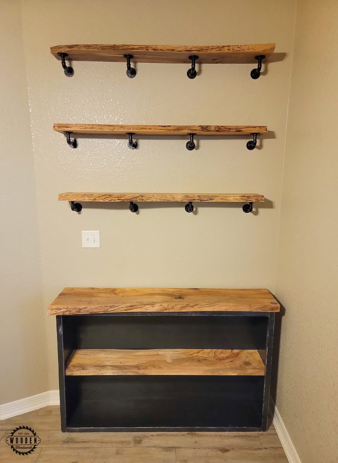 Floating shelves on black pipe-style brackets with pipe coat hooks underneath