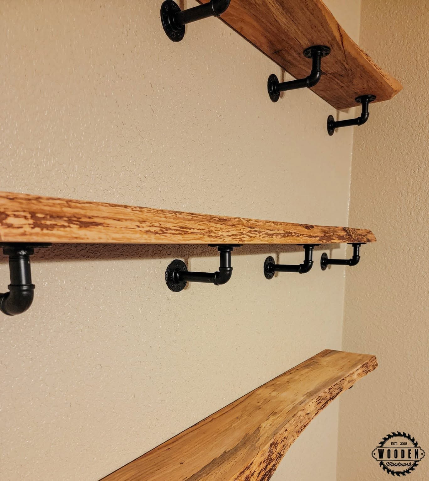 Black pipe-style wall brackets and hooks under floating shelves