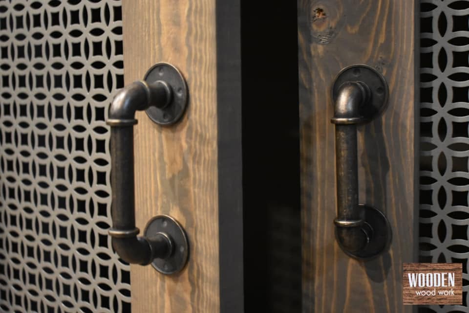 Pair of matching black pipe-style cabinet pulls on dark wood doors