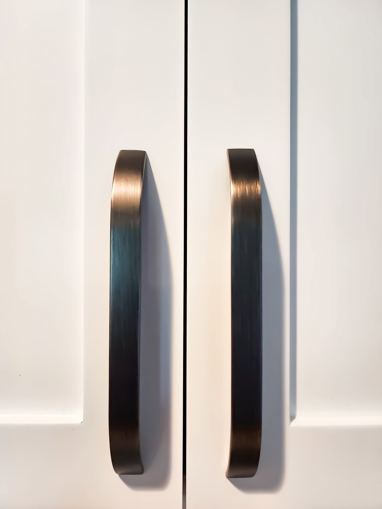Matching bronze arch-style cabinet pulls, close-up detail