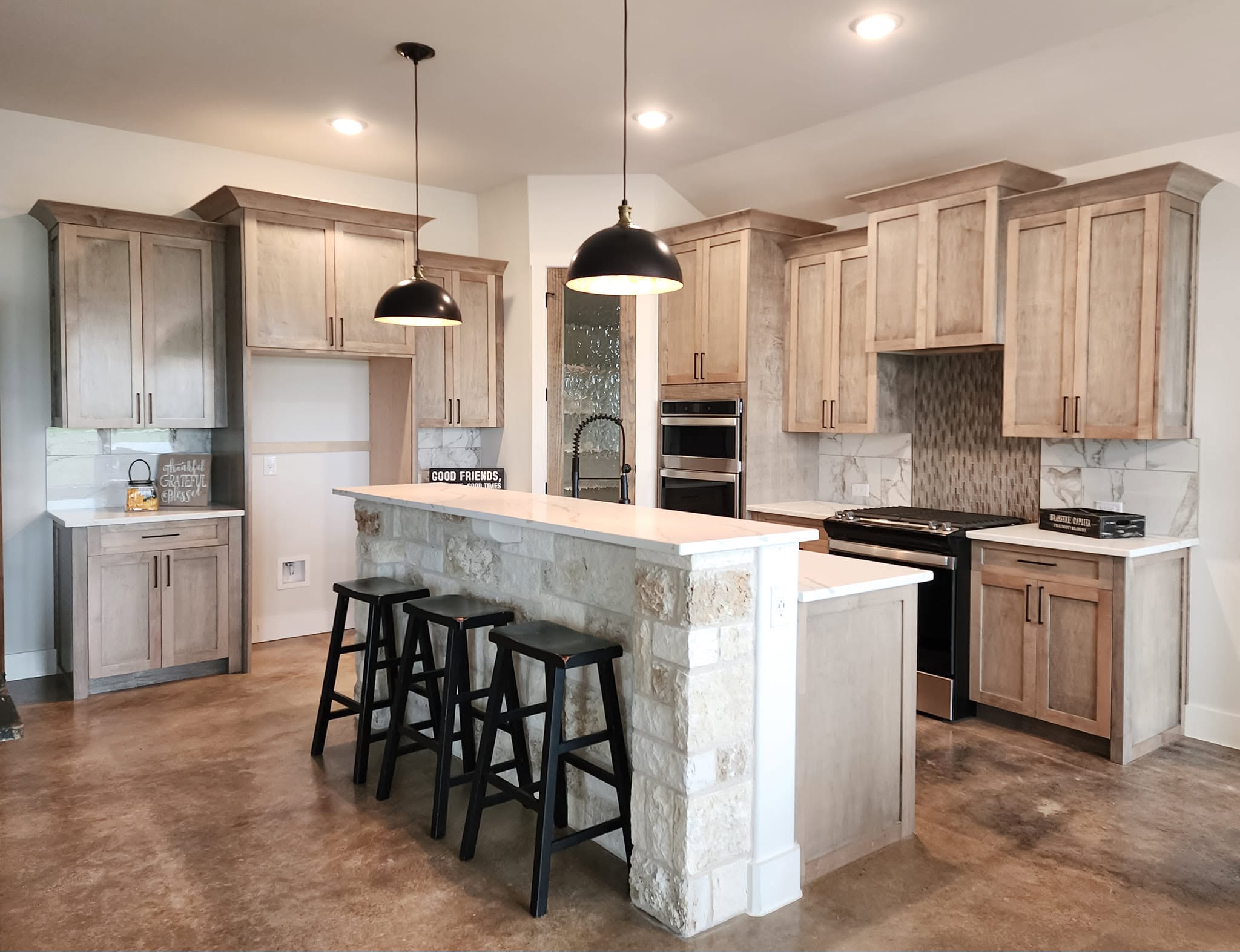 Bronze bar pulls across island, wall, and lower cabinets in a light kitchen